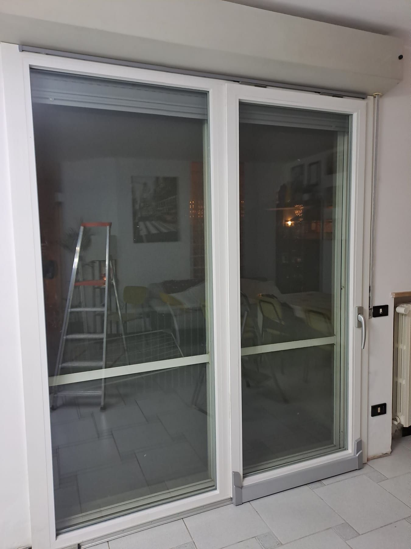Porta-finestra scorrevole a due ante bianca, vista dall’interno del soggiorno