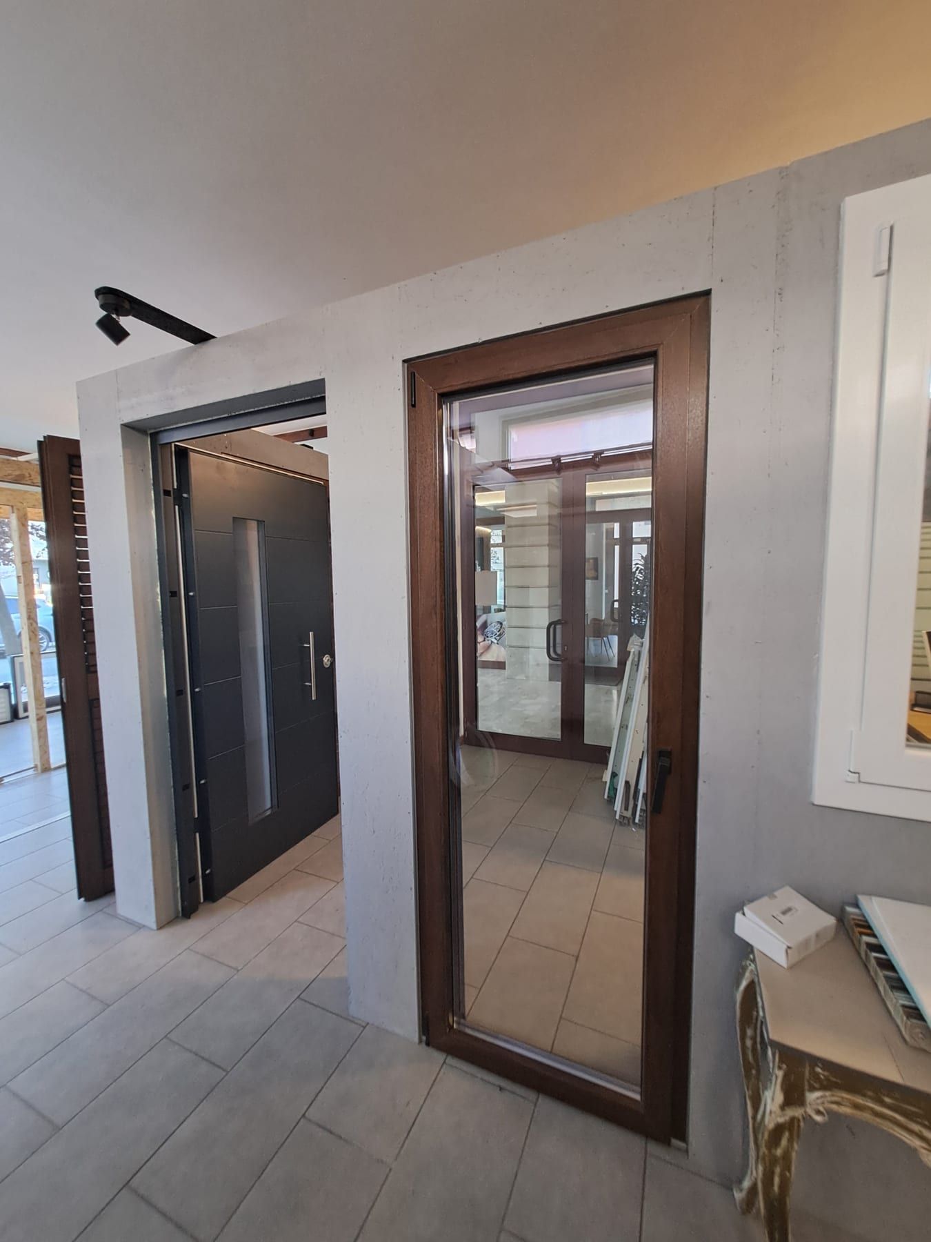 Porta blindata scura e finestra effetto legno esposte nello showroom