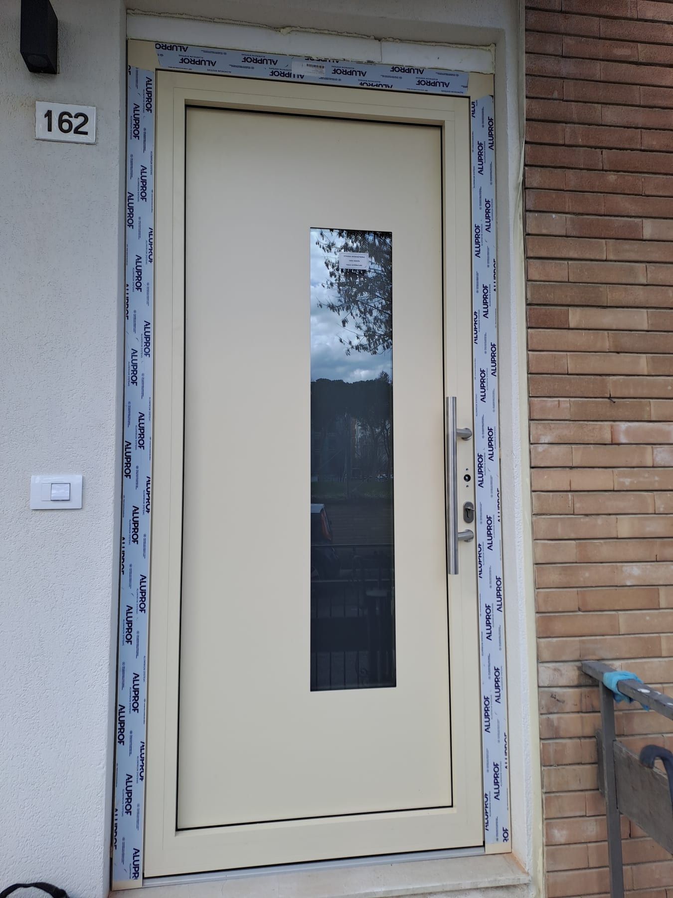 Portoncino d’ingresso avorio con fascia vetrata su una facciata in mattoni
