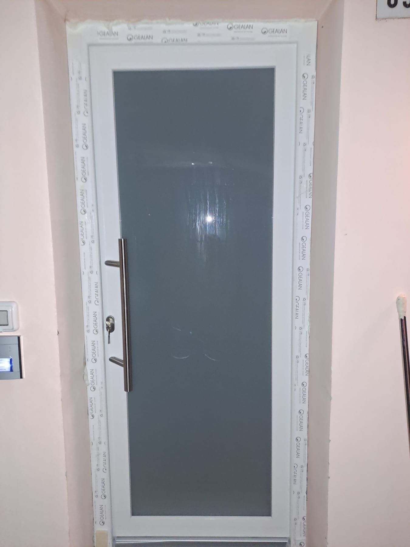 Porta di servizio bianca con pannello grigio e maniglione, appena montata