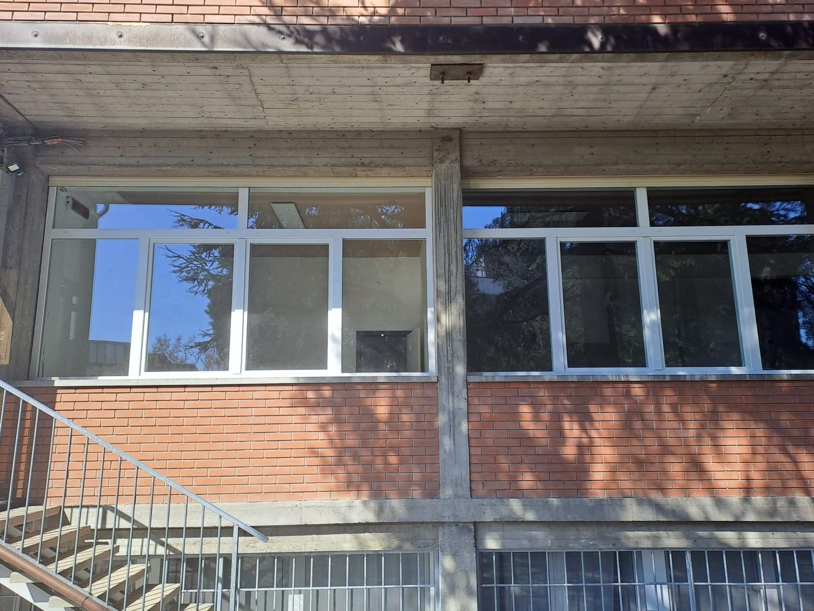 Finestre bianche nuove lungo la facciata in mattoni di un edificio, sopra una scala esterna